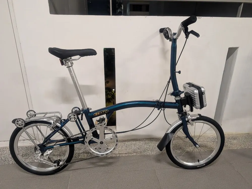 A teal 3Sixty trifold with a silver rear rack and a front bag
