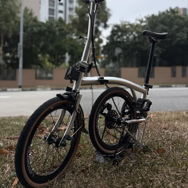 A champagne Leggero trifold with tan-wall tyres on the grass beside a road