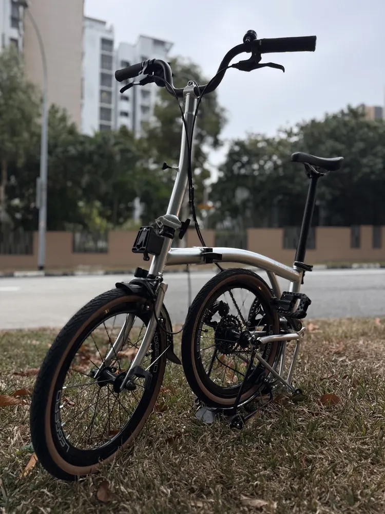 A champagne Leggero trifold with tan-wall tyres on the grass beside a road