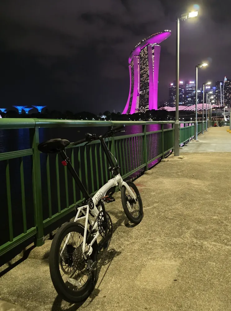 A white folding bike on the Marina Bay waterfront at night