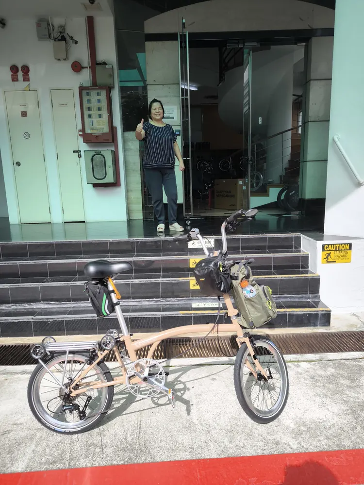A tan Leggero folding bike with front and saddle bags outside AZ @ Paya Lebar