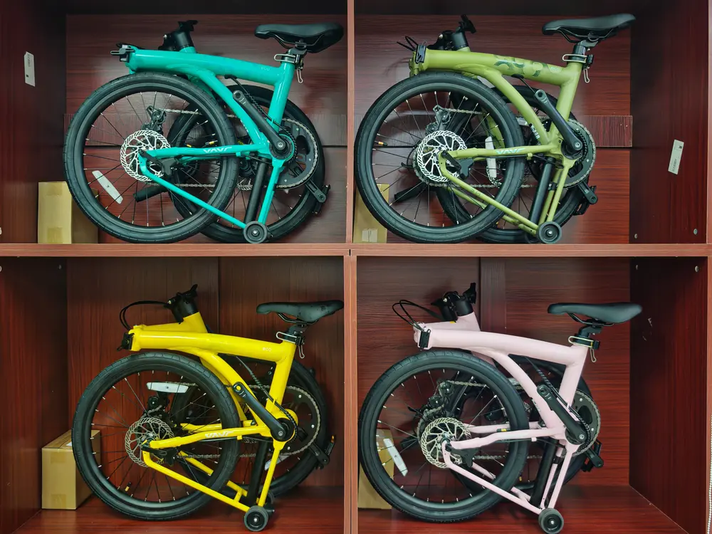 Four folded Java Neo 3 ECO bikes in teal, moss green, yellow and pink in the showroom cubbies