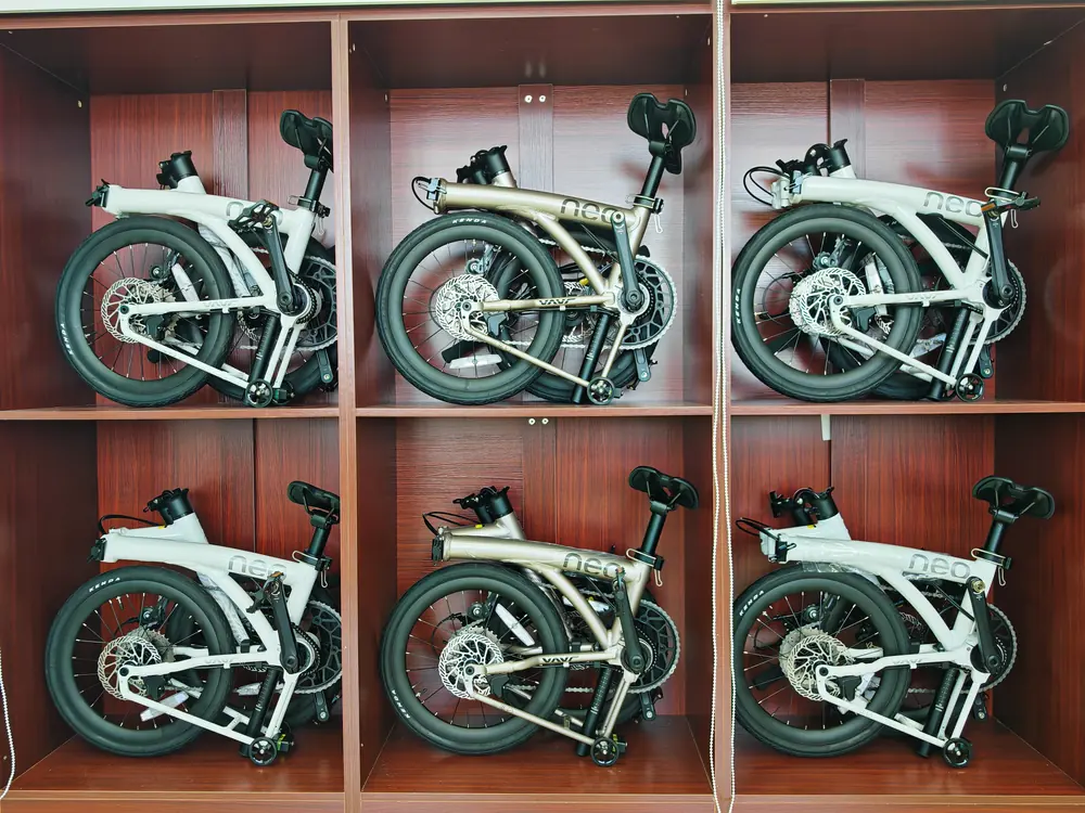 Six folded Java Neo 3 bikes in white and titanium grey, stored in wooden display cubbies